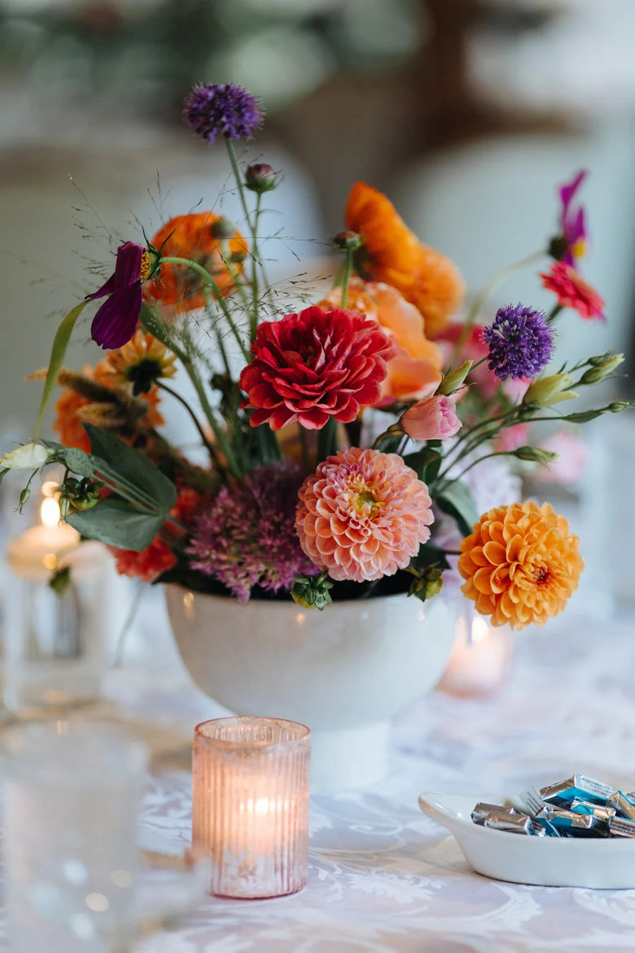 Close up of a bright and colorful floral centerpiece w/ a focus on dahlias and other accent florals.