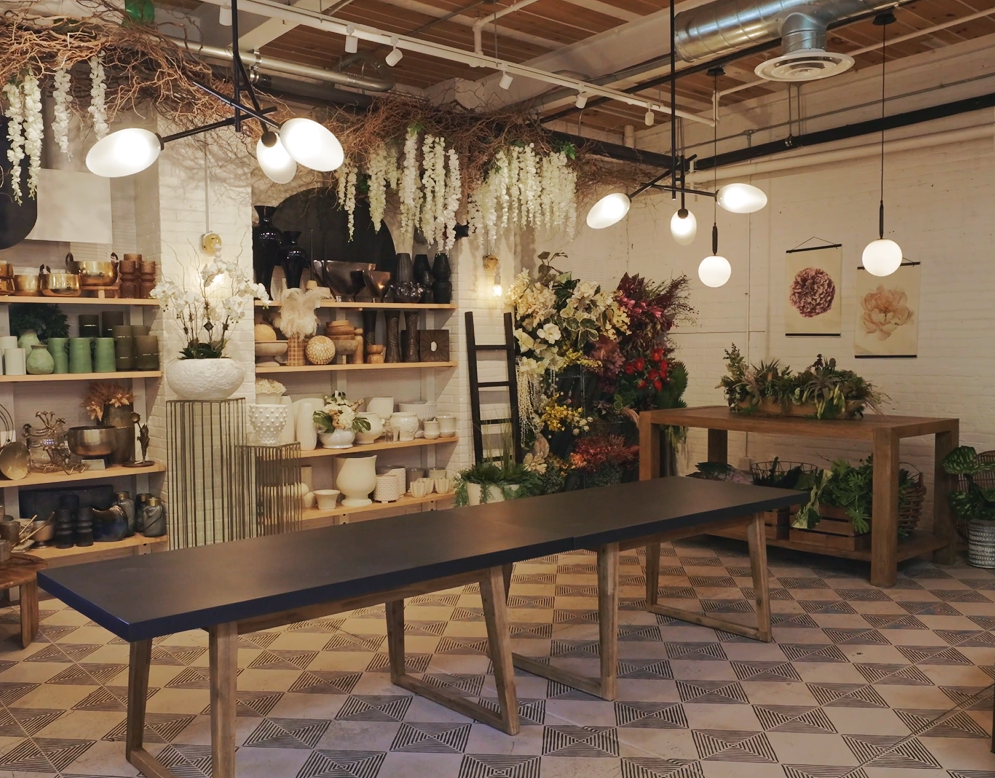 wide view of 53 Russell Street design lab with a wall of vases, everlasting florals, modern light fixtures and a design table