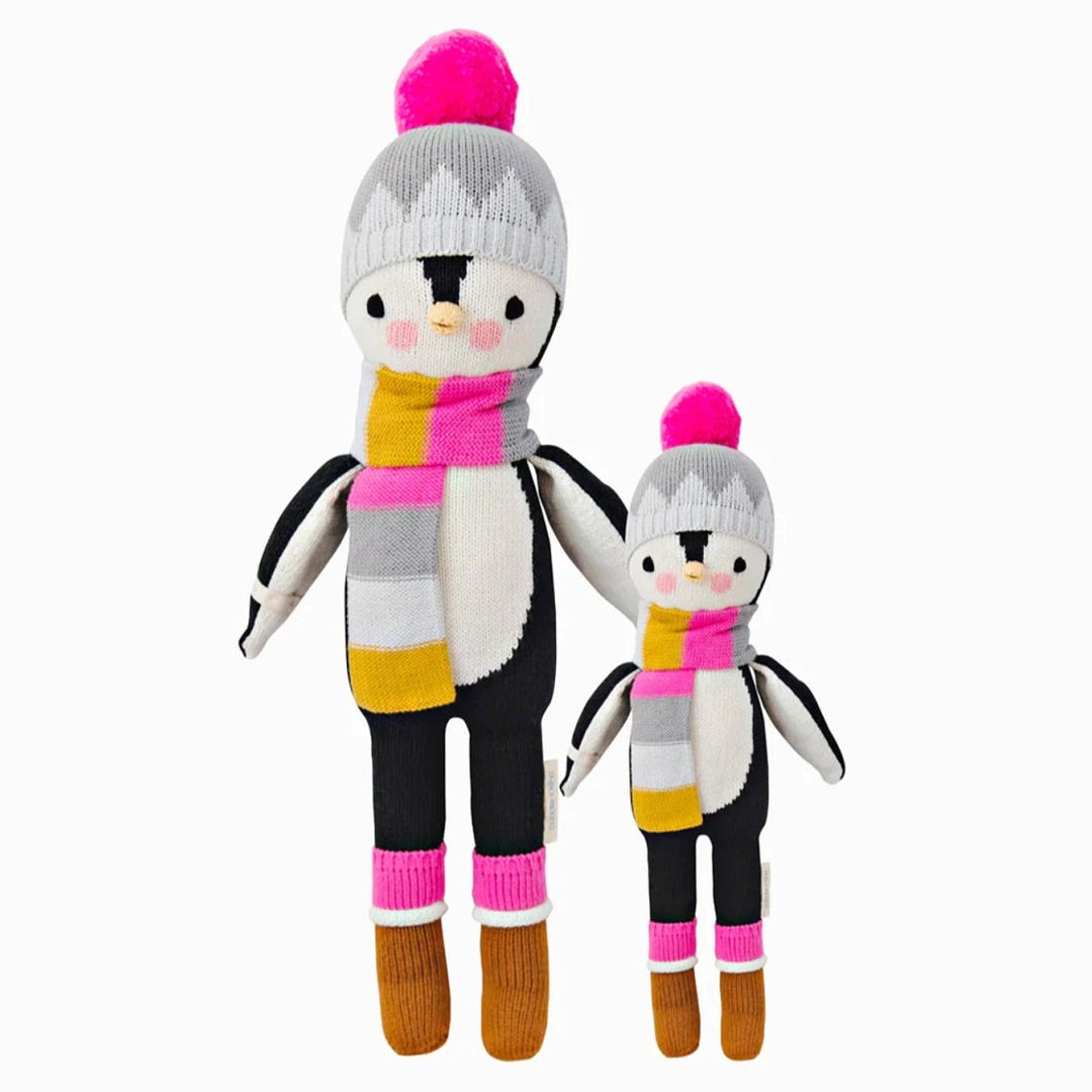 Aspen the Penguin | Cuddle + Kind | A black and white penguin with as scarf, hat, and boots in pink/yellow/gray/brown/white. Two sizes shown, 20" and 13".