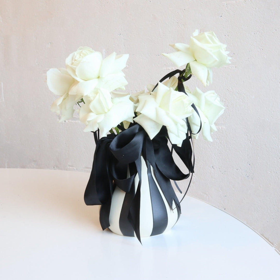 black and white striped vase with white roses accented with black ribbon.