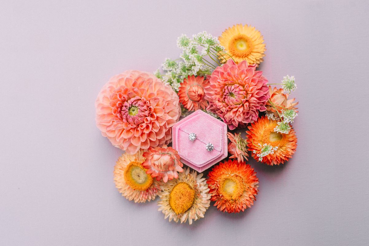 flat lay of coral blooms with diamond earings.