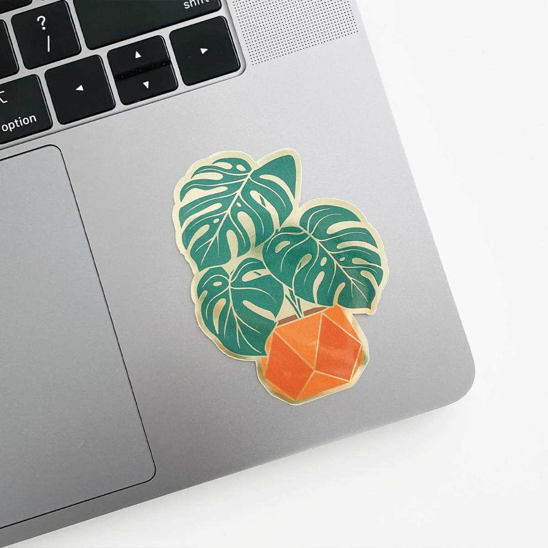Paper Anchor Co. Monstera Sticker | A monster plant sticker in  an orange pot with gold accents.