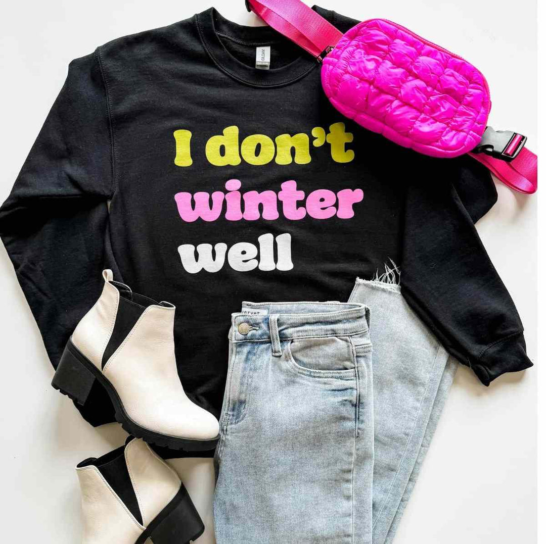Mugsby | I Don't Winter Well Crewneck | A black pullover with yellow, pink, and white text.