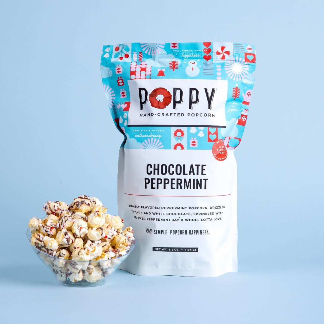 Poppy Hand-Crafted Popcorn | Chocolate Peppermint Popcorn | A white and blue bag with red accents. A small bowl of popcorn is placed next to the bag.