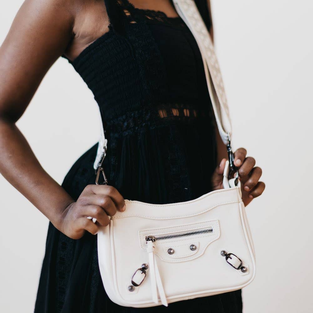 A cream crossbody bag with a silver zipper and hardware details.