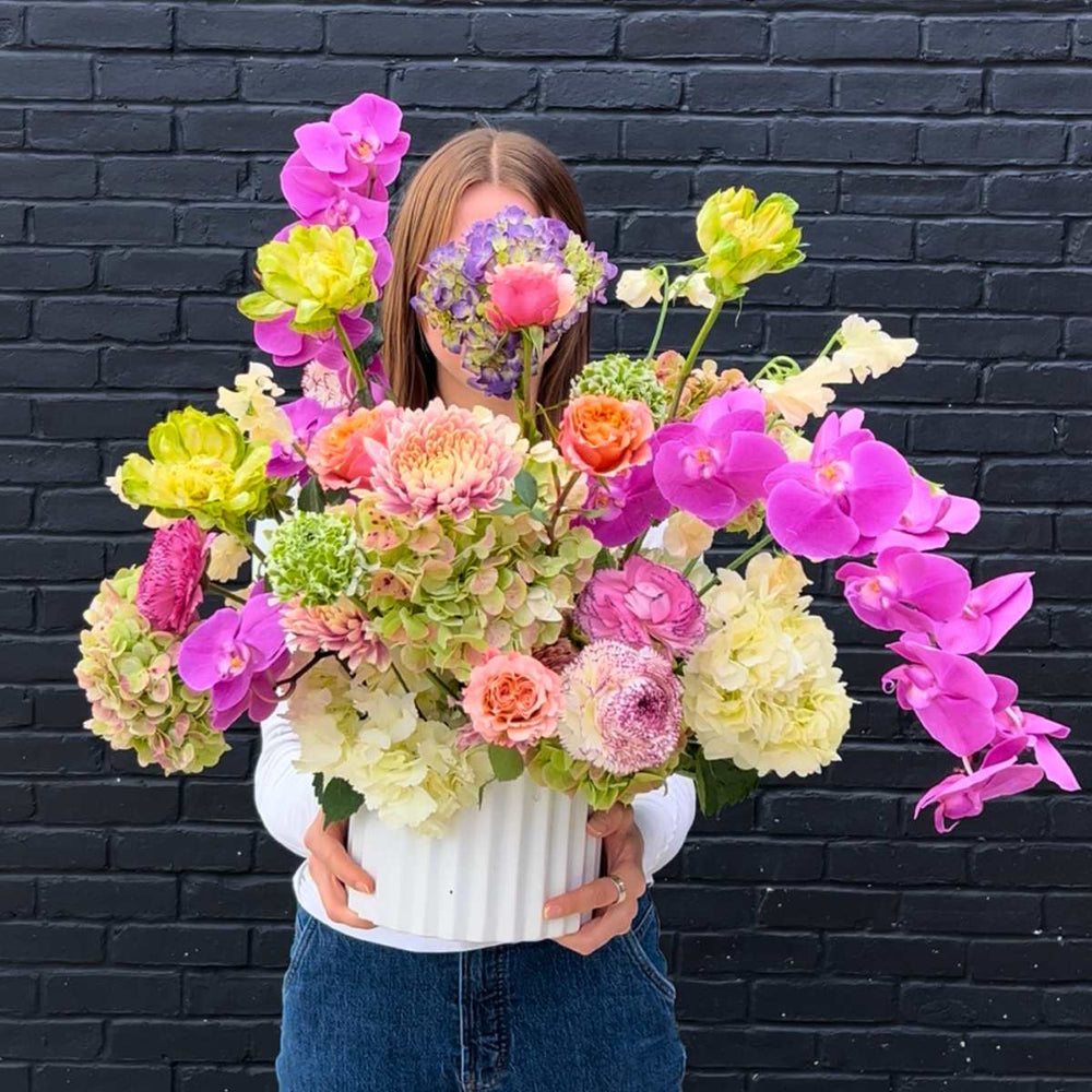 Stacy K Floral | Ethereal Blooms | A large flower arrangement with a variety of blooms such as magenta orchids, green hydrangea, and purple roses.