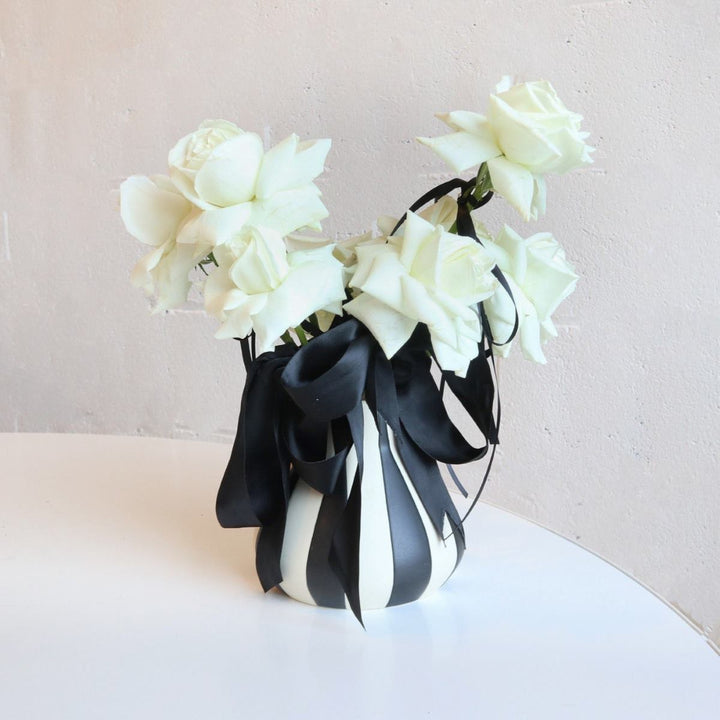 Stacy K Floral | A black and white arrangement with white roses, black ribbon, and a white/black striped vase.