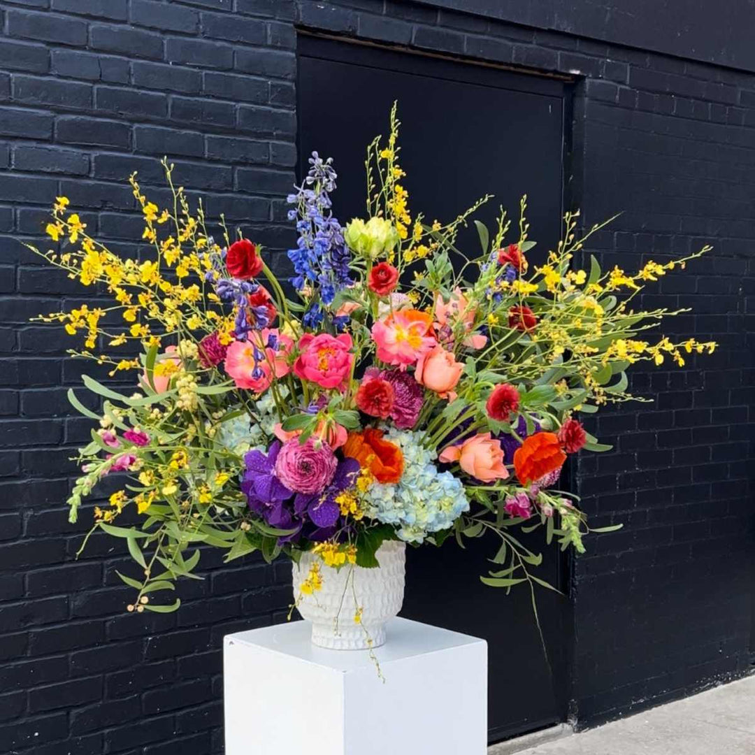 Stacy K Floral | Wild Symphony | A large bright arrangement with a variety of flowers such as orchids, peonies, hydrangea, roses, delphinium, and more.