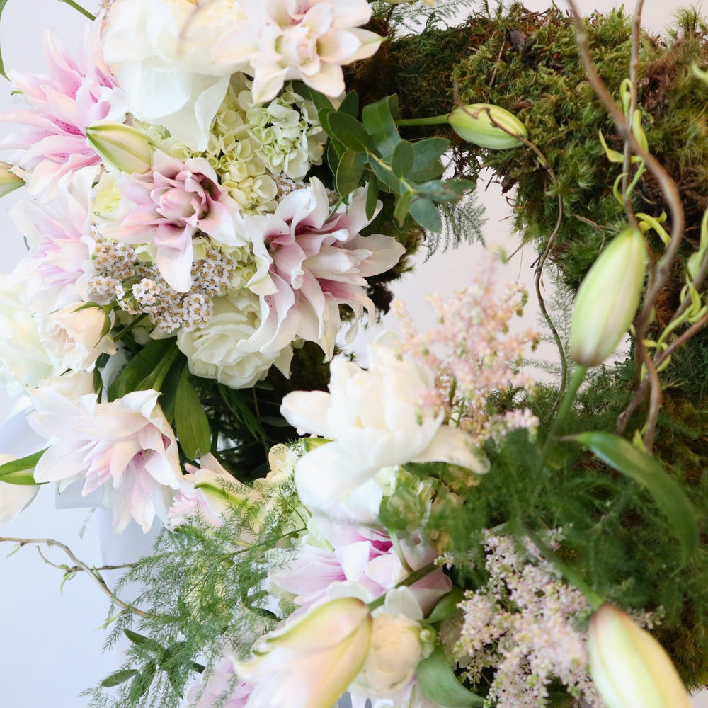 Garden Sympathy Wreath | A close up on the wreath, showcasing the double lilies, roses, hydrangea, greenery, and moss.