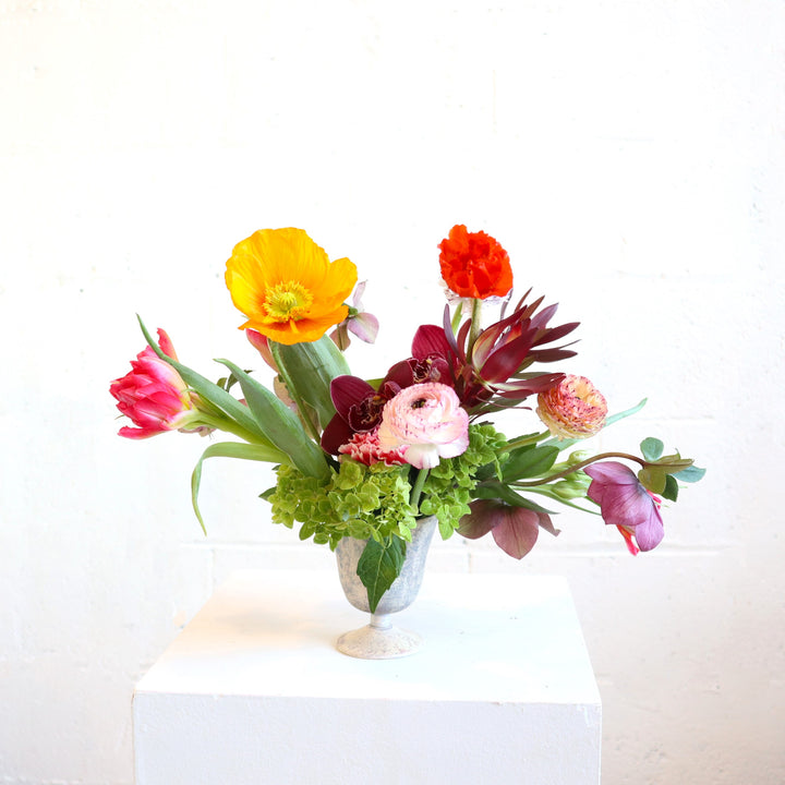 poppy, orchids, tulips. hydrangea, ranunculus  and heleborus in a vase on a white background.