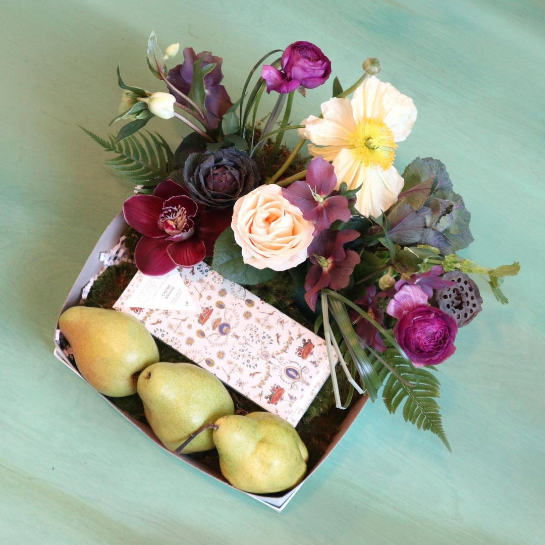 Fruit box with three pears, Compartes chocolate and a floral arrangement with helleborus, poppies, kale, orchis, ranunculus.