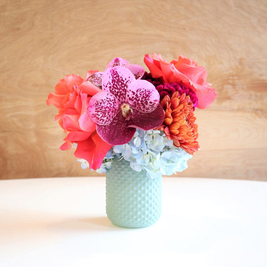 Fairy | Vased Arrangement | A blue vase with roses, mums, orchids, and hydrangea. Colors are pink, purple, and blue.