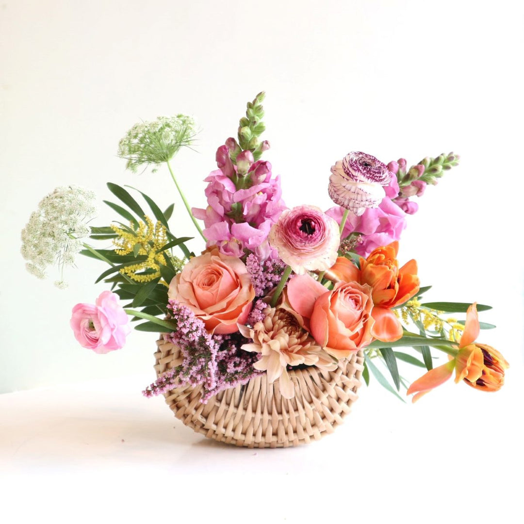 Basket of spring flowers with ranunculus, snapdragons, tulips, queen annes lace, heather, acacia.