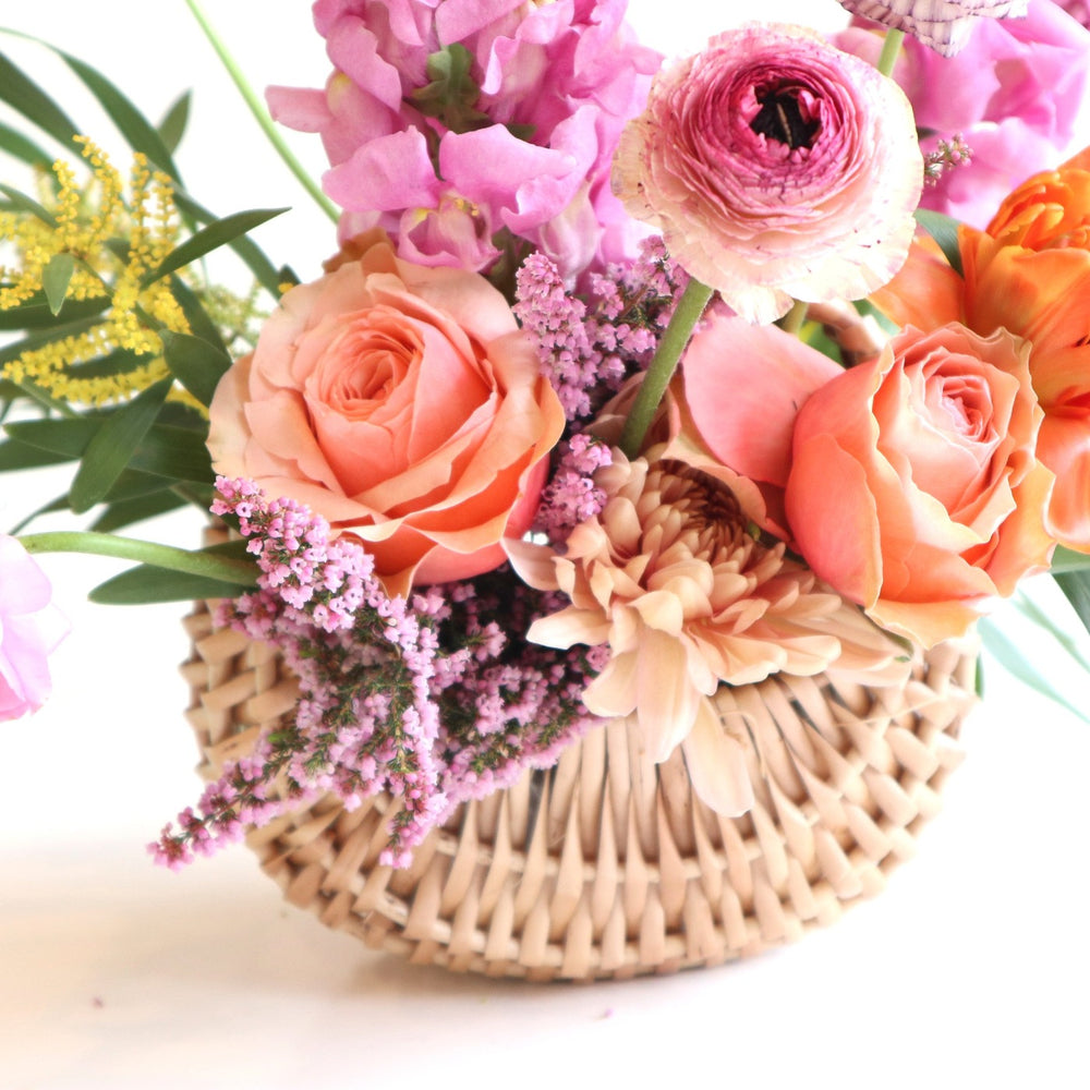 close up of Basket of spring flowers with ranunculus, snapdragons, tulips, queen annes lace, heather, acacia.