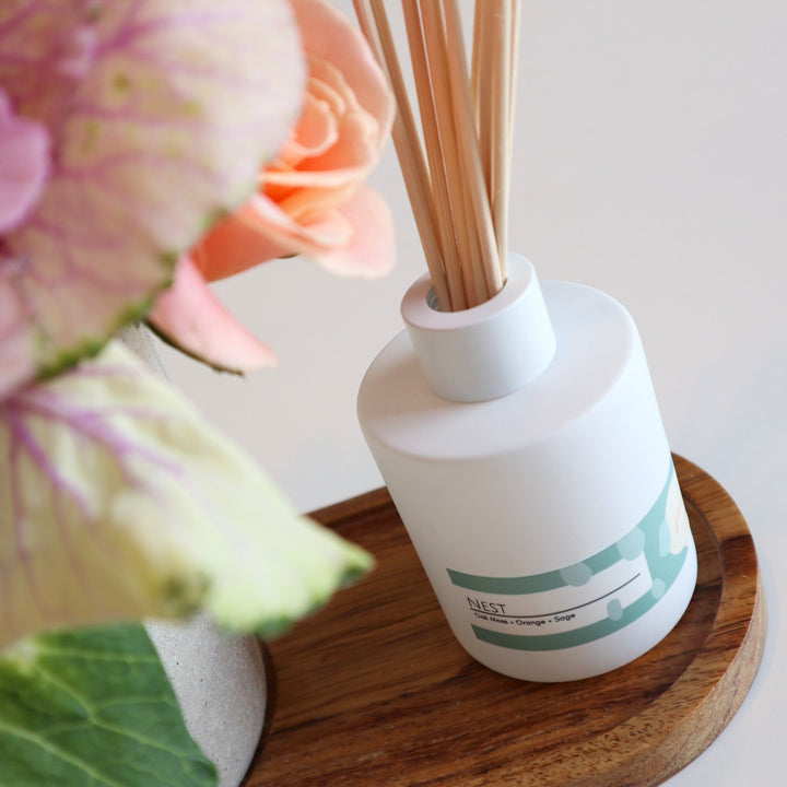 Fleurish and Floral Gift Set | Close up of the reed difuser with the scent being "NEST" with a close up of the wooden tray it is placed on.