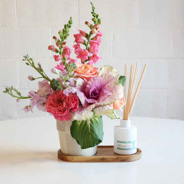 Fleurish and Floral Gift Set| This Gift set includes a Fleurish Co. Diffuser  with a custom designed Floral arrangement with a cream and gray checkered vase and tray to compliment. The Arrangement has two pink snapdragons, purple kale, one pink garden rose, two coral roses and three light purple stock.