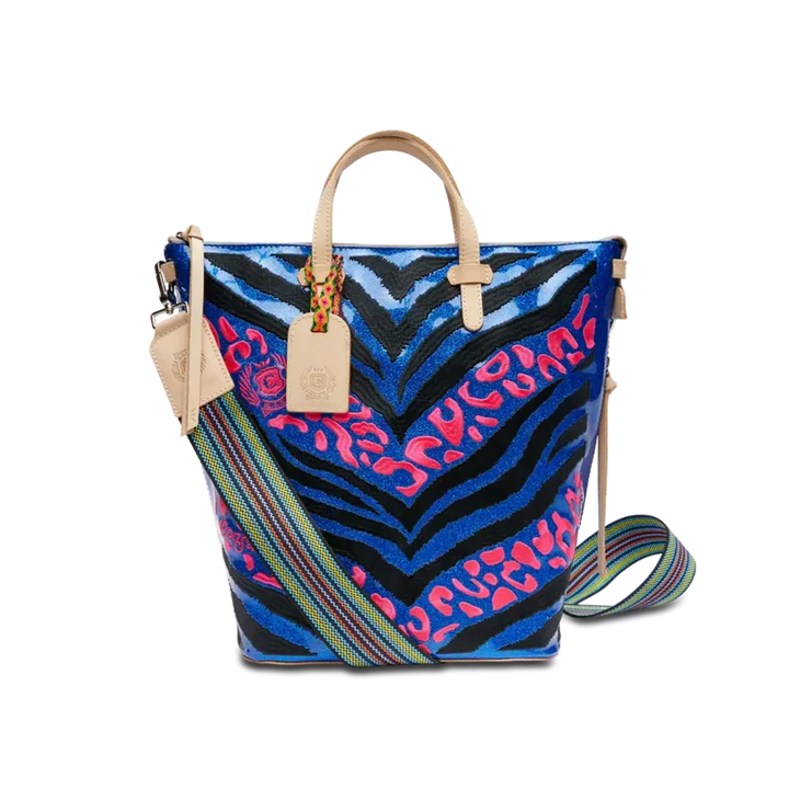 Liv Sling | Consuela | Handbag with a blue/black/pink zebra pattern on the front, multi color strap, and diego leather accents/handle.