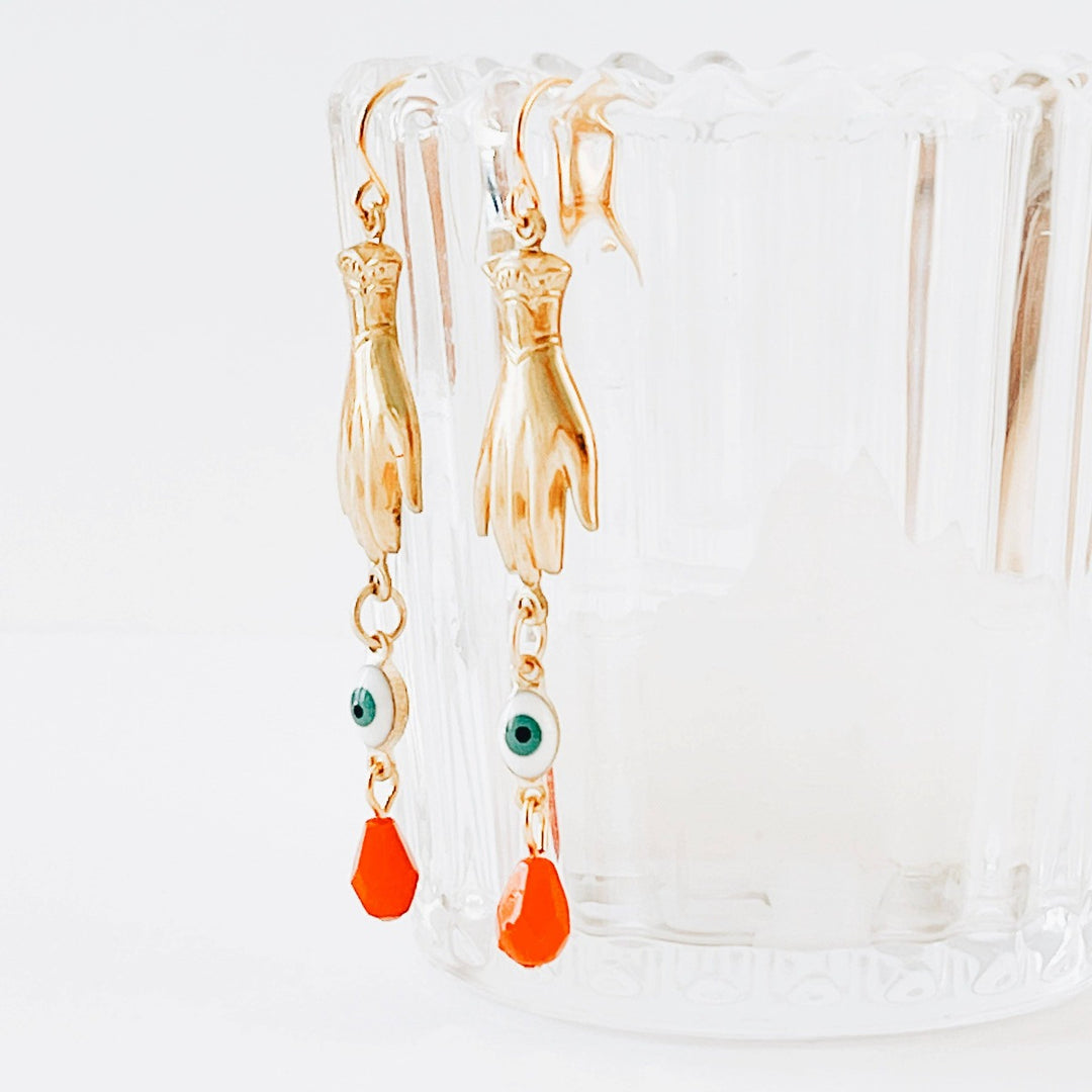 Nest Pretty Things | Evil Eye Dangle Earrings | Gold dangling earrings with a tiny hand, evil and red drop bead. Hanging off of a clear glass.