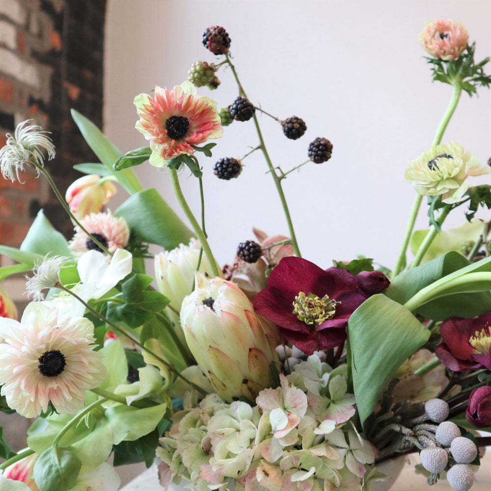 An arrangement with anemone, protea, helleborus, tulips, berries, brunia and hydrangea.