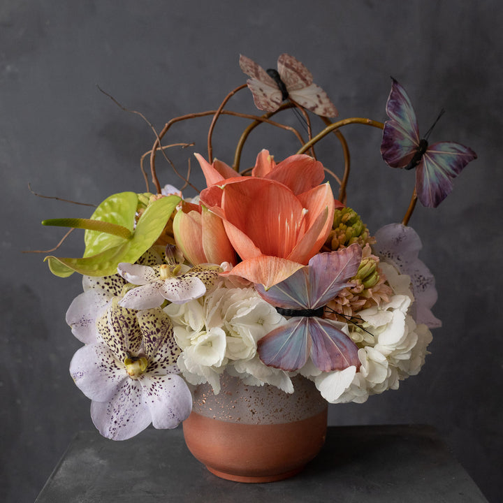 Rose gold container with pastel flowers accented with butterflies.  Rochester NY flowers delivery