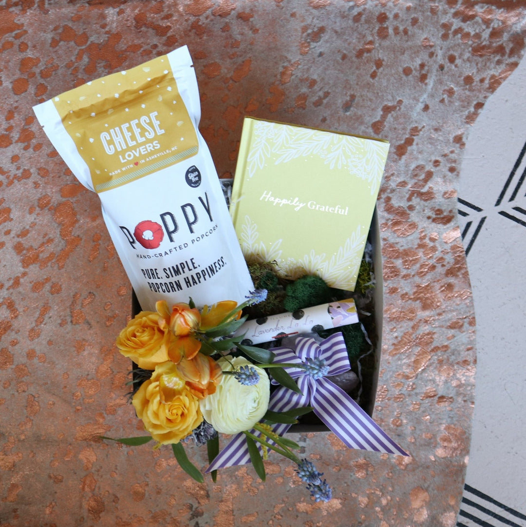 Thank You Gift Box | A spring gift box the Poppy Popcorn "Cheese Lovers" Popcorn, a small spring arrangement with yellow, blue, orange, and white, a perfume, and a yellow book titled "Happily Grateful".