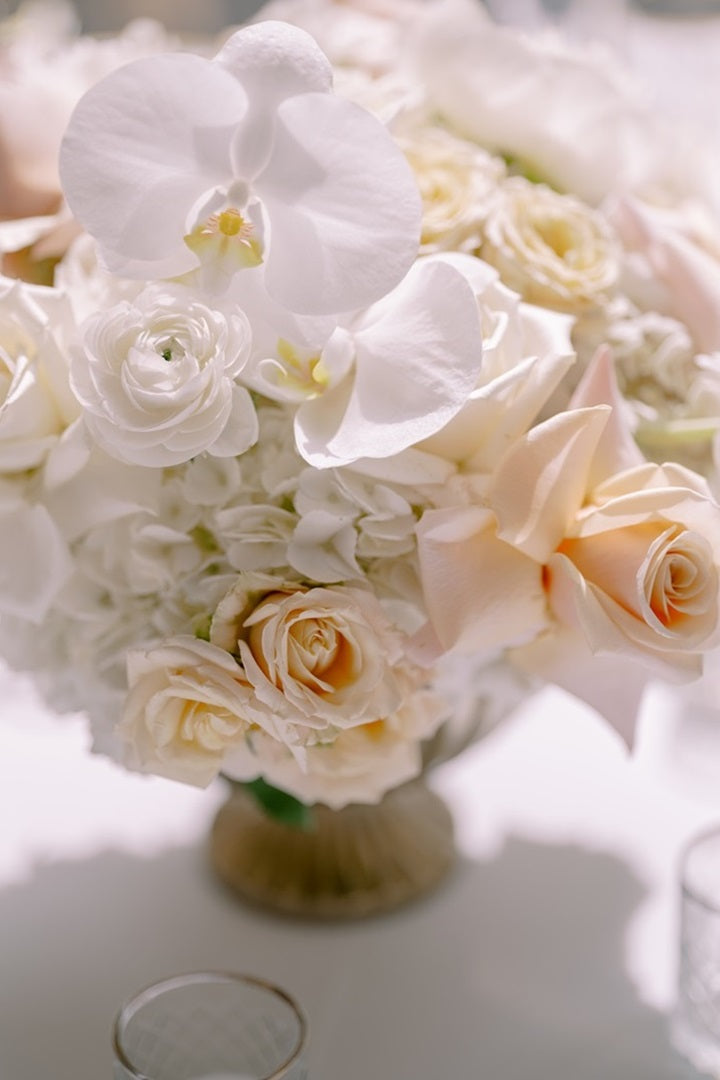 A white and blush bouquet with orchids, hydrangea, roses, and ranunculus.