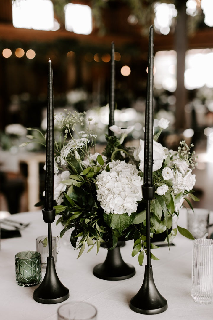 Floral arrangement in the reception hall of the Colloca Estate Winery. Tables set in the white, green, and black color palette. Arrangement is accompanied by black taper candles and clear/green votives.