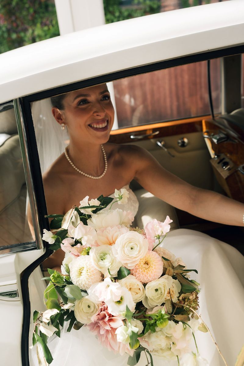A bride getting out of a car holding a beautiful bouquet