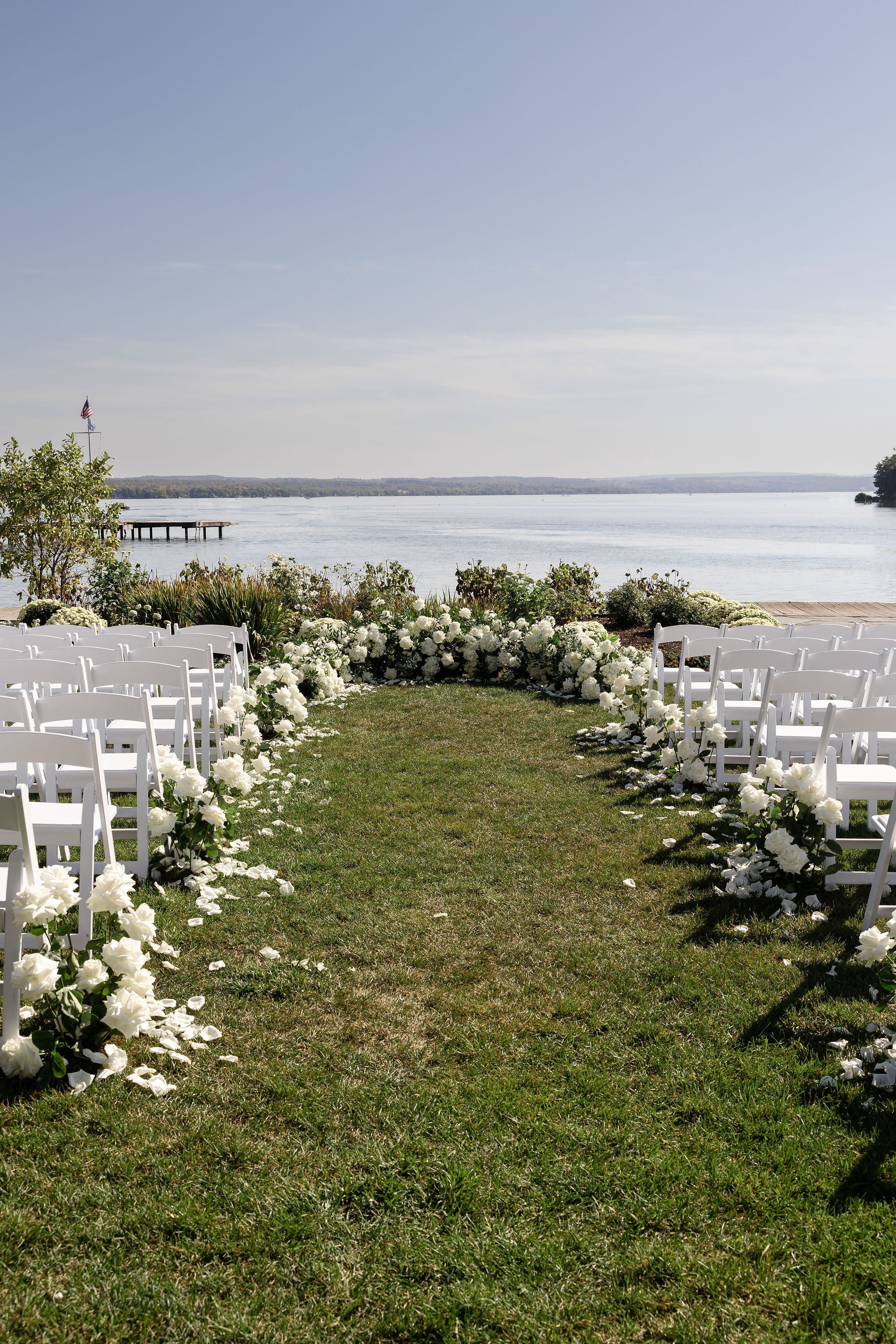 Ceremony set up on a lake with white florals surrounding the altar and aisle