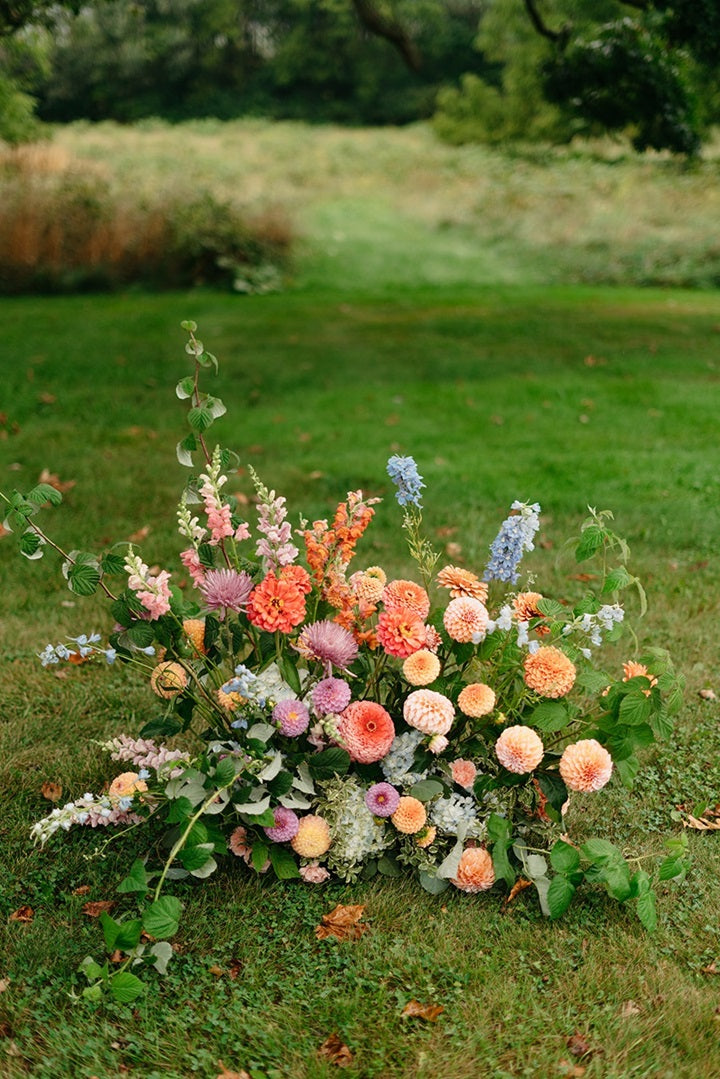 Close up on a large colorful floor arrangement. It is a rainbow of colors with florals such as dahlia, hydrangea, zinnia, snapdragons, and more.