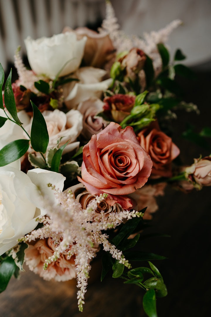 Close up on the bridal bouquet with roses and greenery in white/pink.