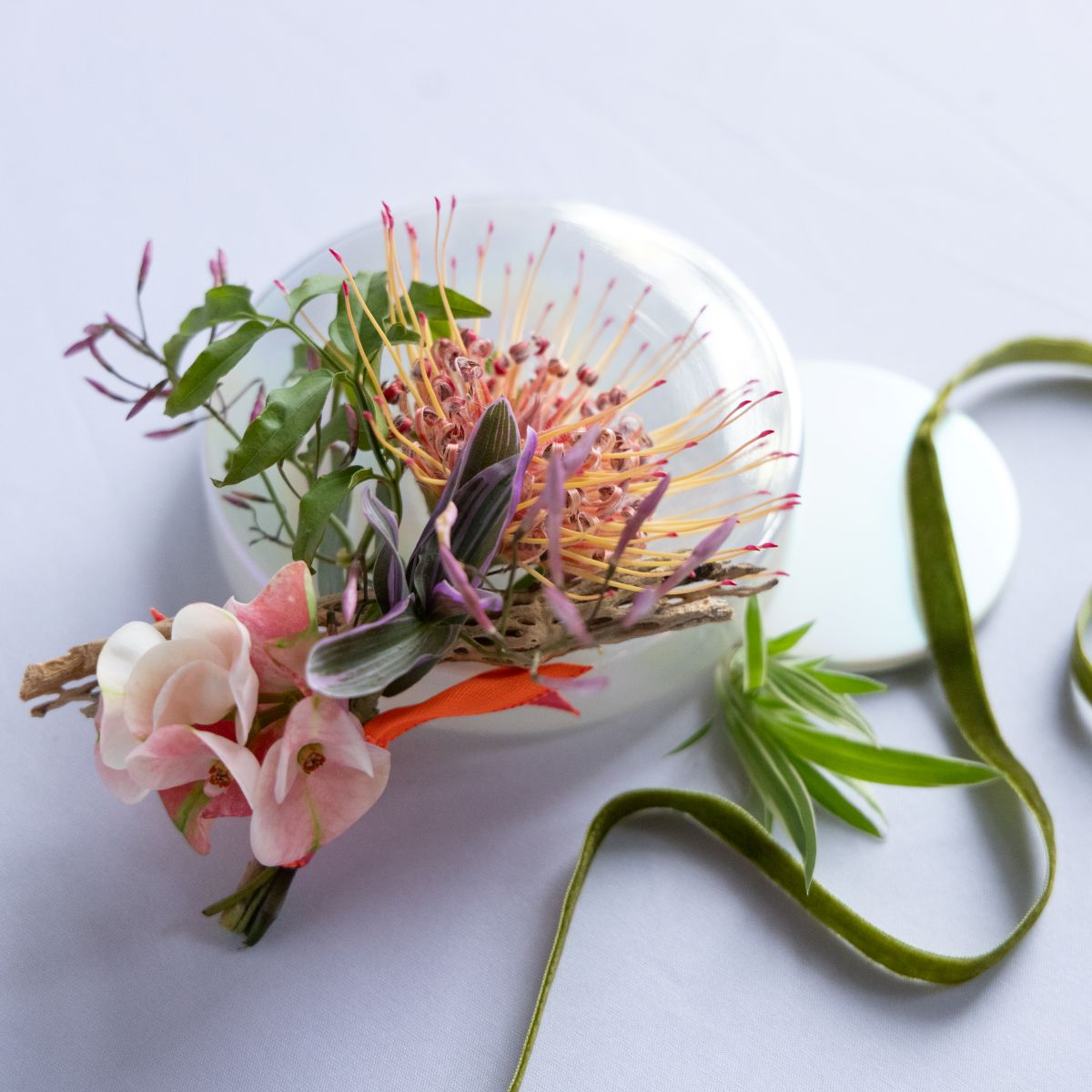 boutonniere with pink and green colors and pin cushion flowers as the focal