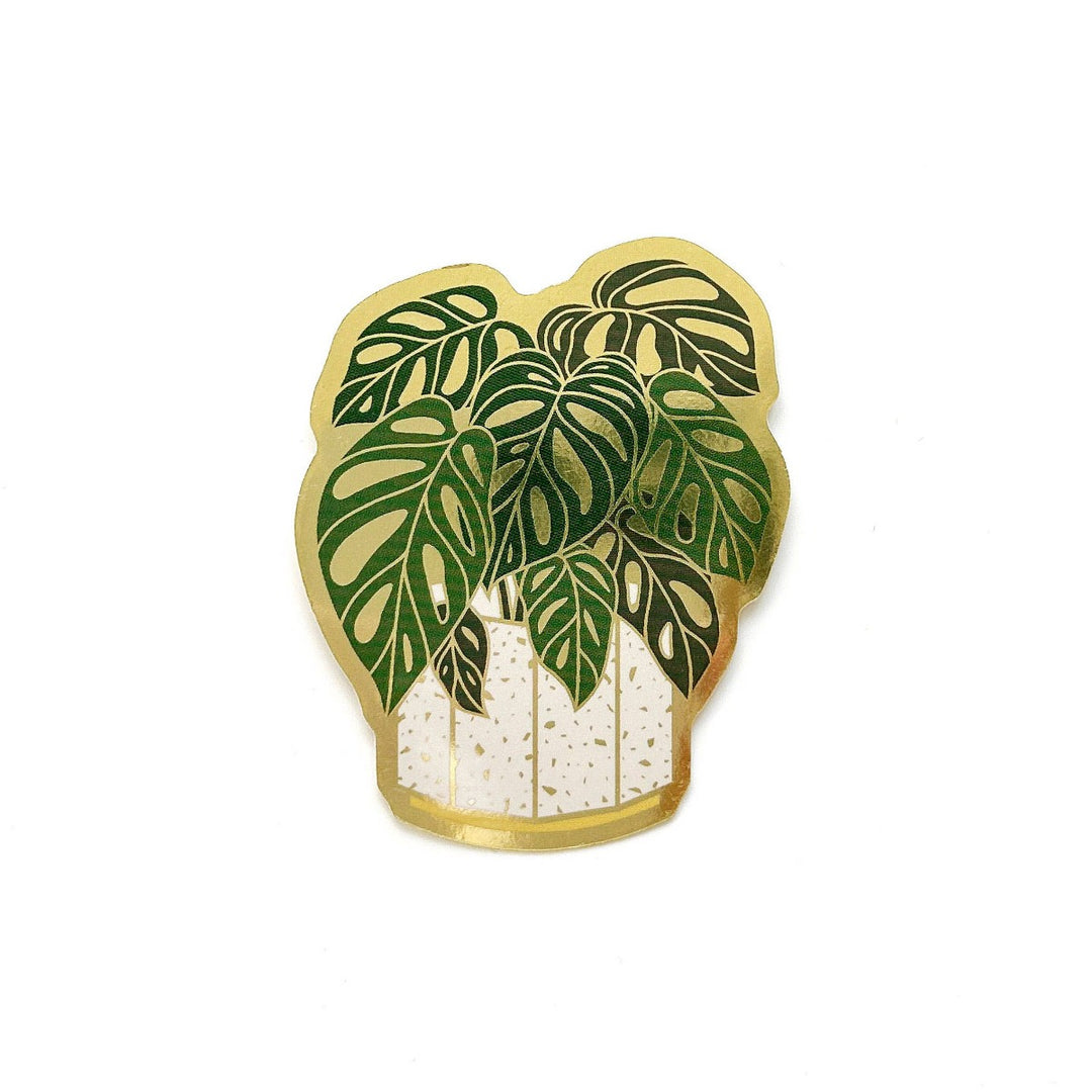 Swiss Monstera Plant Sticker | A green plant with a white pot and gold accents.