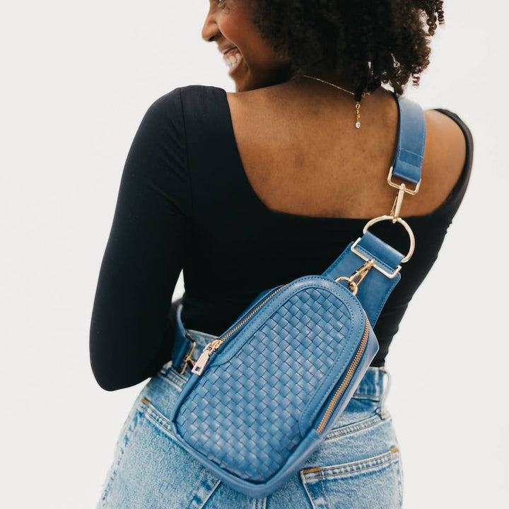 A blue crossbody bag with a woven texture and gold hardware.