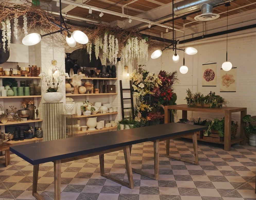 wide view of 53 Russell Street design lab with a wall of vases, everlasting florals, modern light fixtures and a design table 