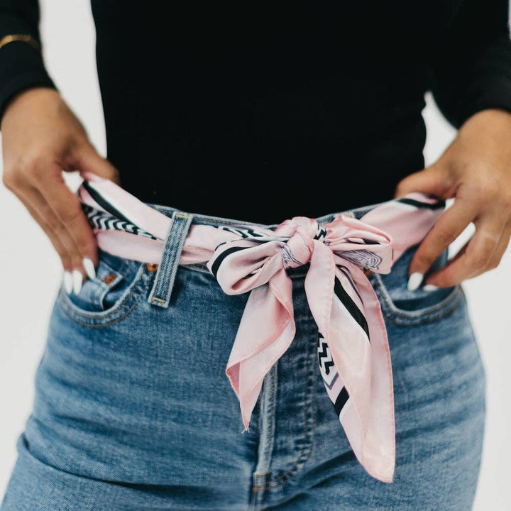 A pink, black, and white patterned hair scarf being used as a belt.