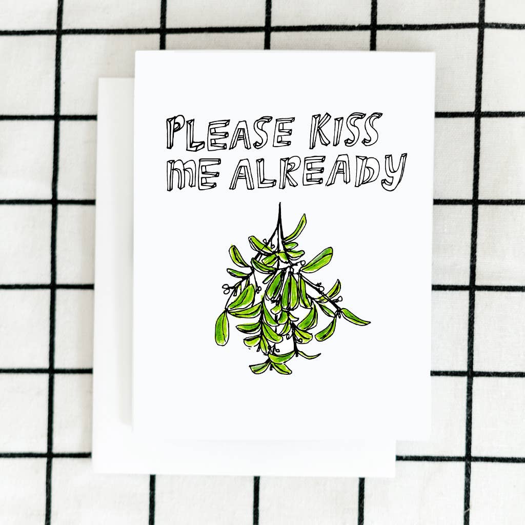 ARTJADEN | Mistletoe Greeting Card | A white card with text "Please kiss me already" and an illustrated sprig of mistletoe.