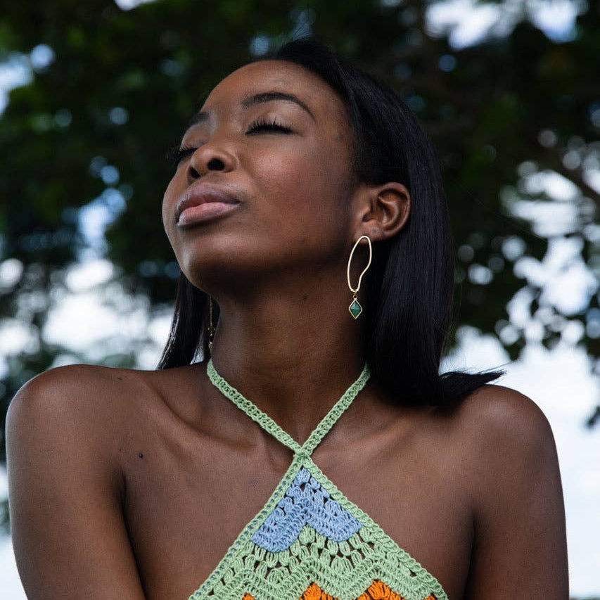 Woman wearing a colorful crochet top with a blurred natural background