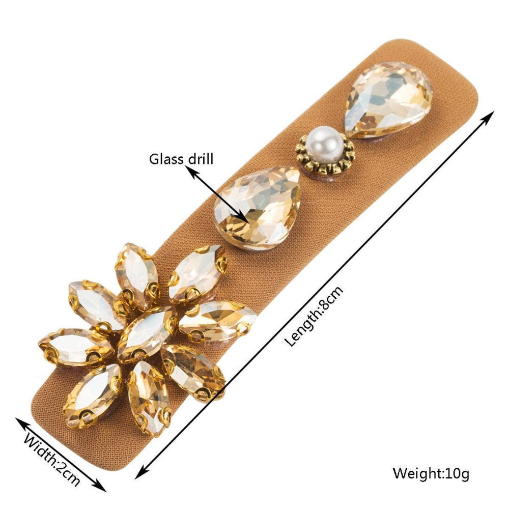 Accity | A brown hairpin with clear studded jewels. Dimensions: 2cm wide, 8cm long.