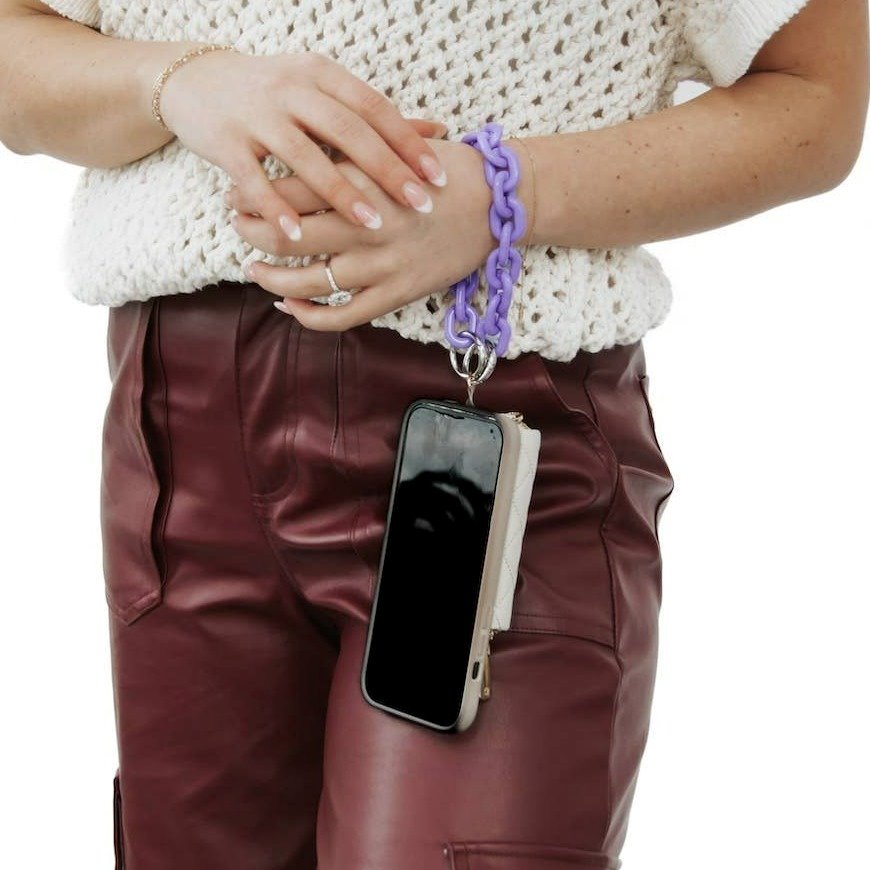 An acrylic phone chain in purple hanging from the model's wrist.