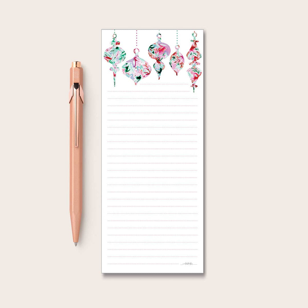 Amanda Klein Co | Ornaments Notepad | Green, red and pink ornaments on a white notepad with pink dotted lines.