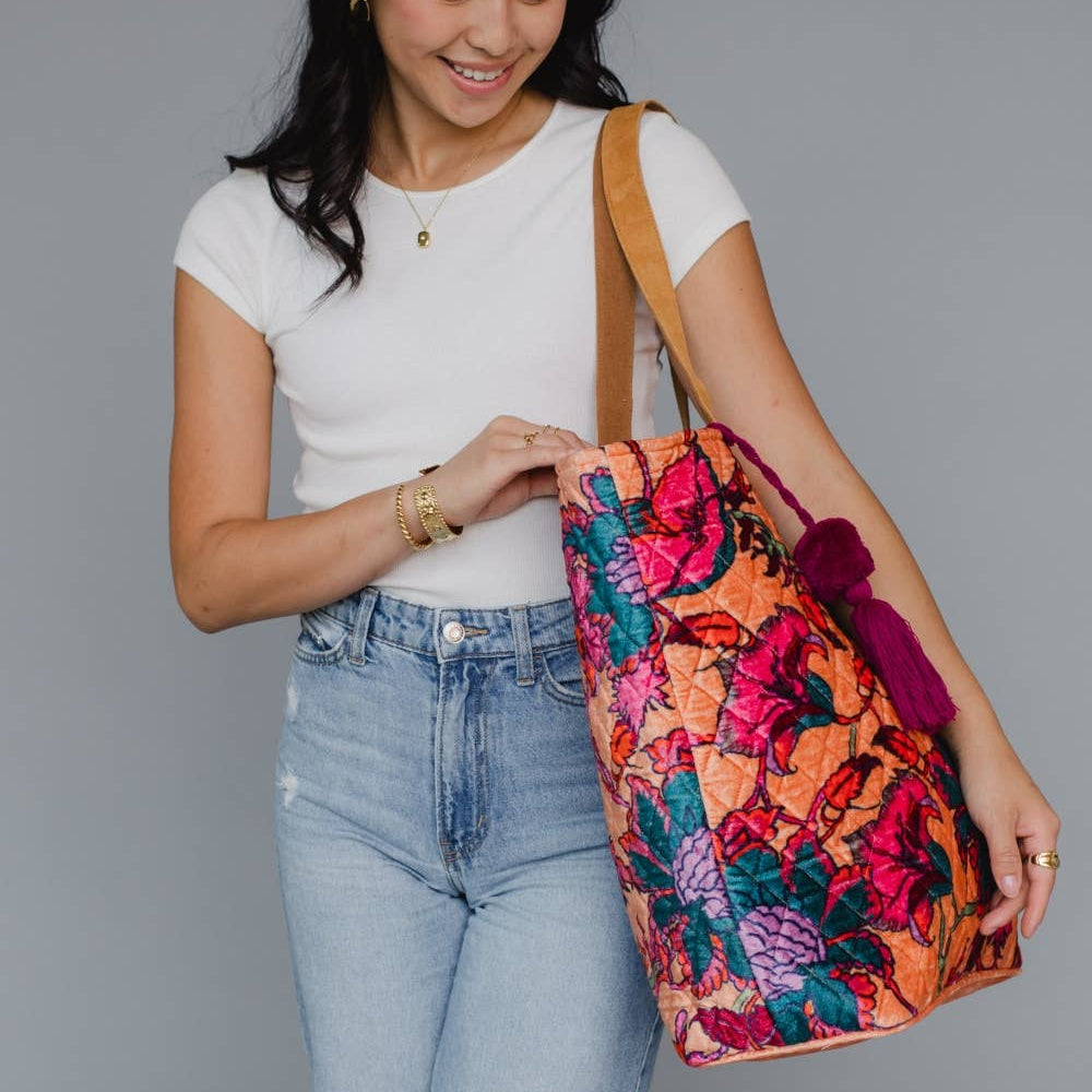 Woman holding a colorful floral bag against a gray background