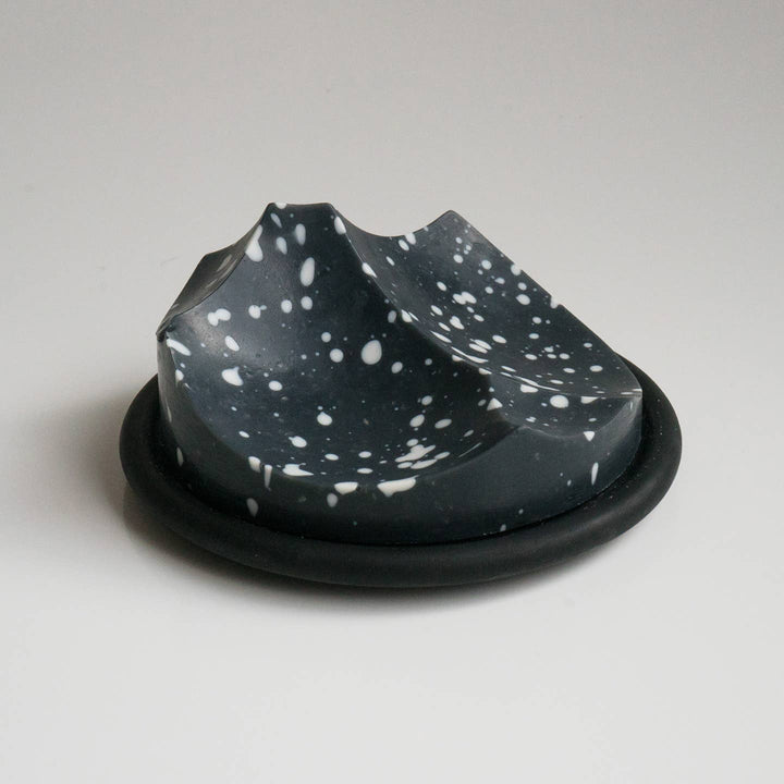 Speckled black and white ceramic dish on a plain background