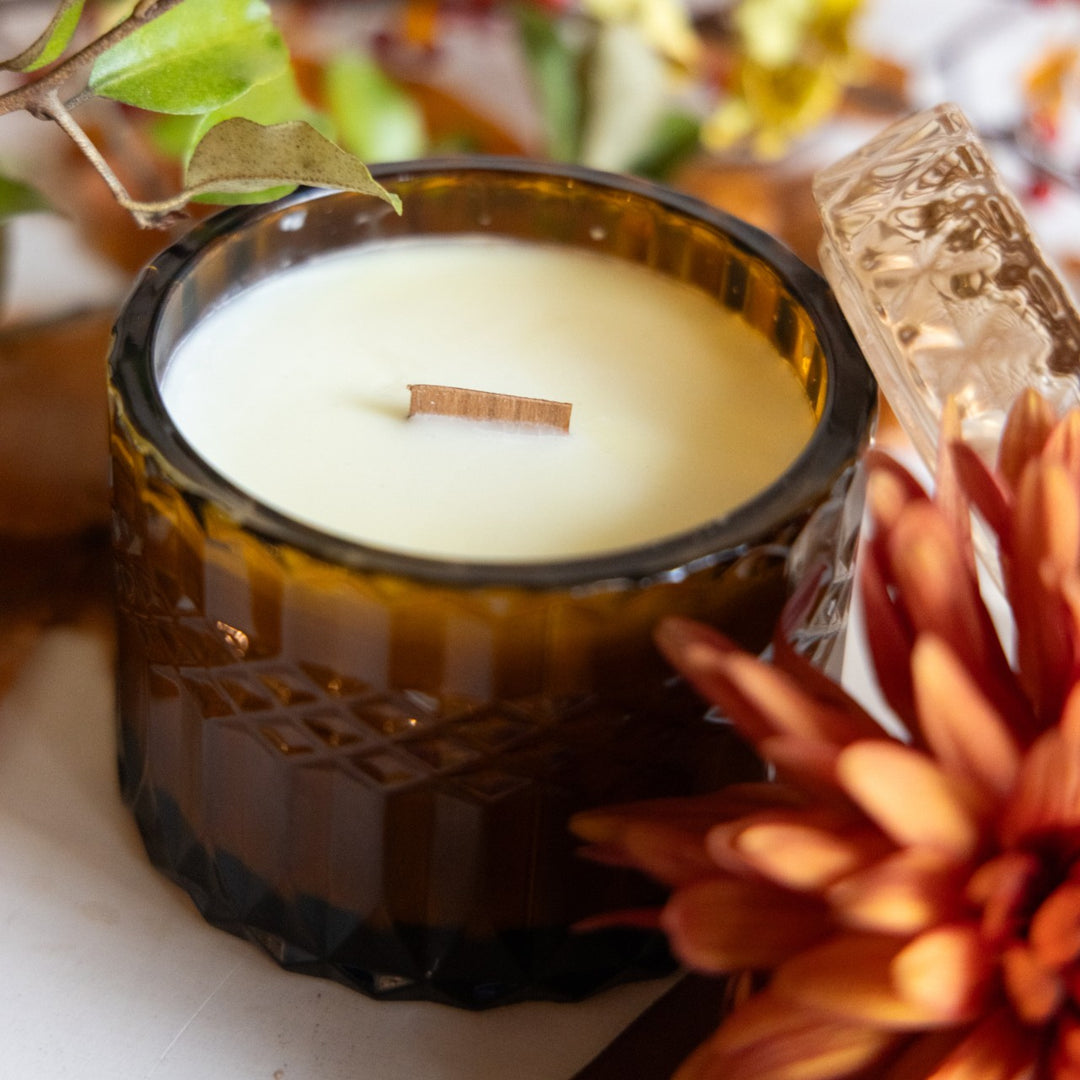 Candle in a decorative glass holder with autumn-themed elements