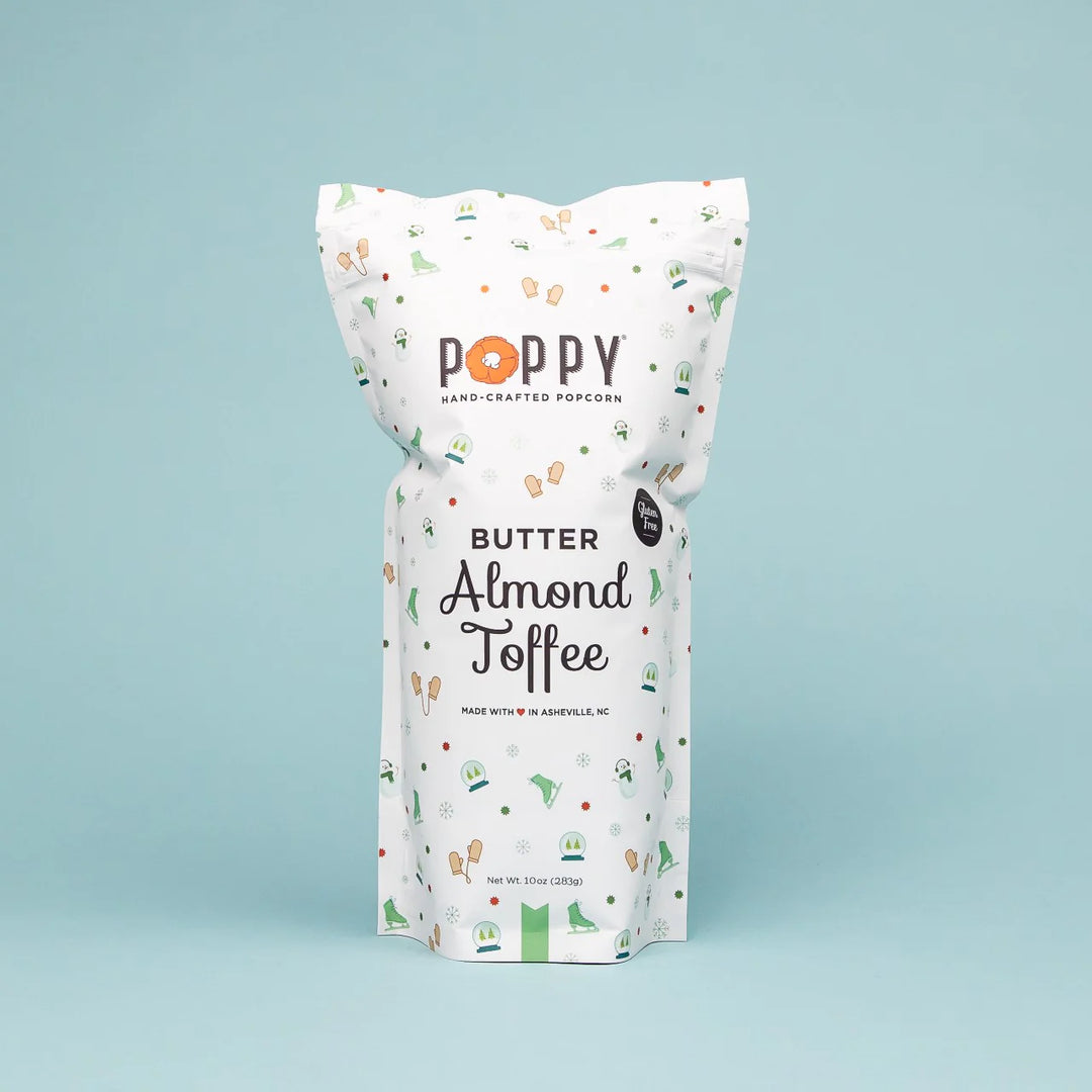 Holiday Poppy Popcorn | A white bag with ice skates, mittens, snowmen, and snow globes. Text reads "Poppy Hand-crafted Popcorn, Butter Almond Toffee, Made with love in Asheville, NC, gluten free."