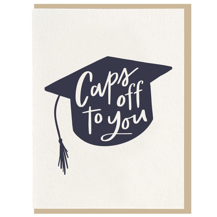Caps Off To You | Dahlia Press | A simple white card with a blue color block graduation cap with white calligraphy text "Caps off to you". Comes with a natural brown envelope.