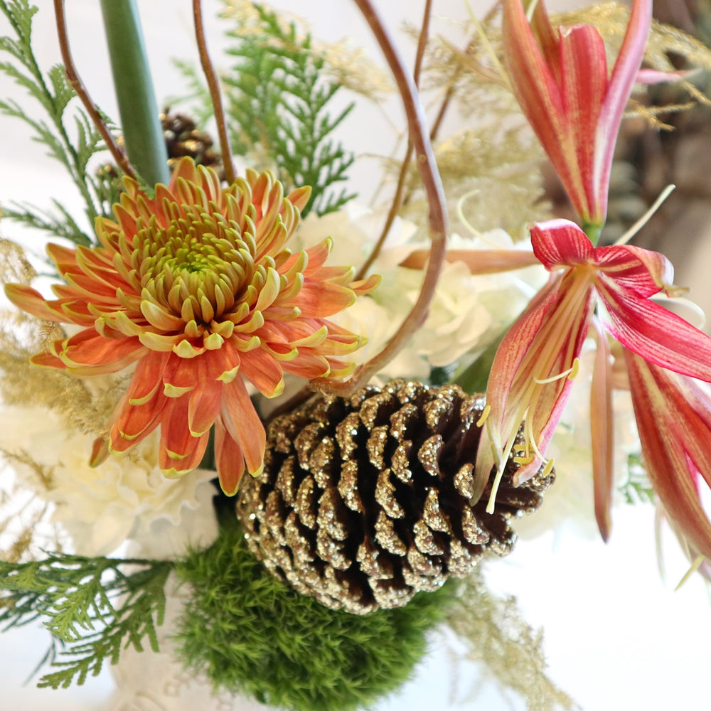 Christmas Spice | Close up on the mum, lily, and glittering gold pinecone.