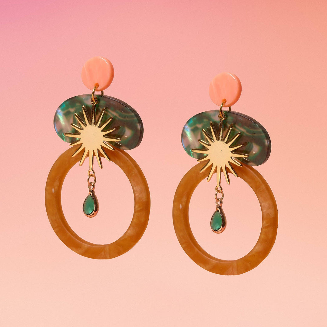 Pair of earrings with circular design on a pink background