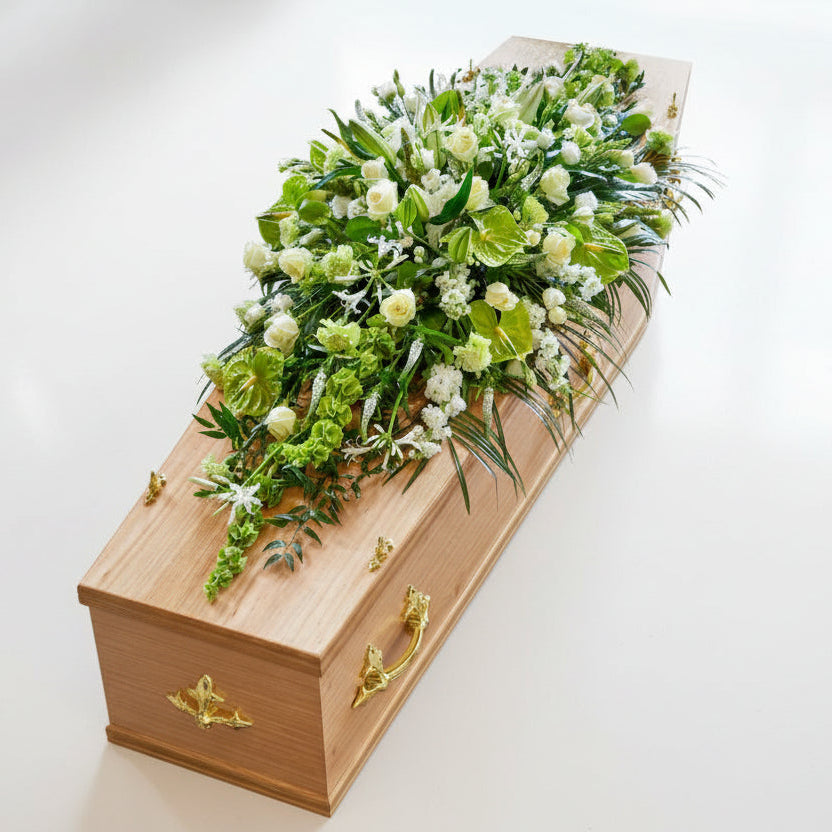 Casket with green and white floral arrangement