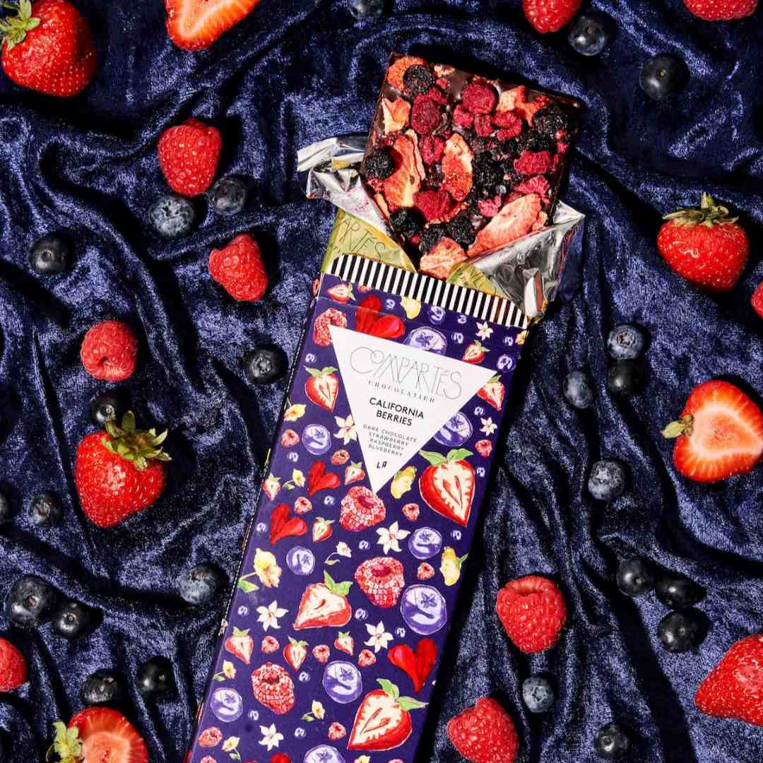 Compartes Chocolate | California Berries Dark Chocolate Bar | A blue velvet backdrop with blueberries and strawberries.